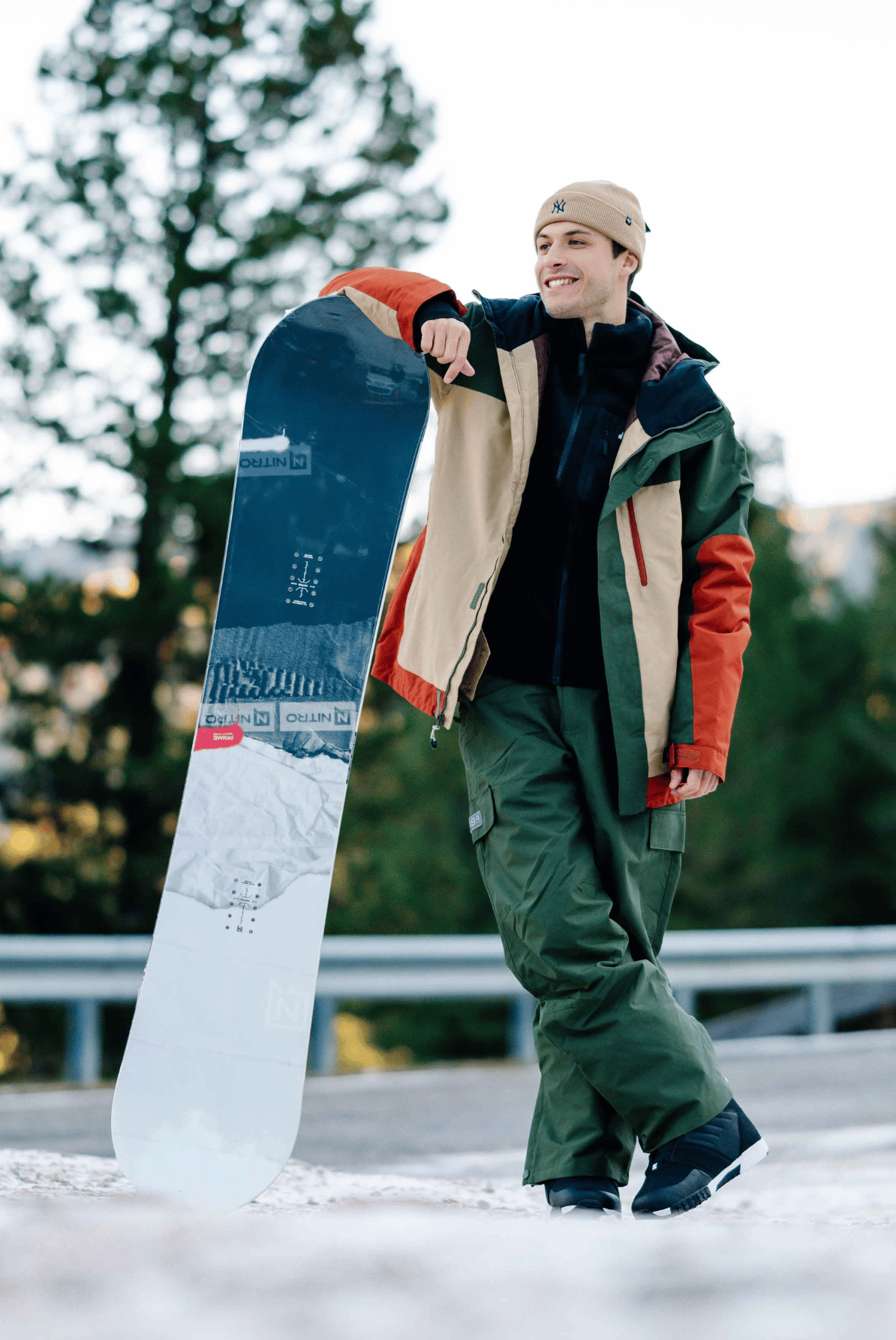 Mann mit Snowboard und mehrfarbiger Winterjacke