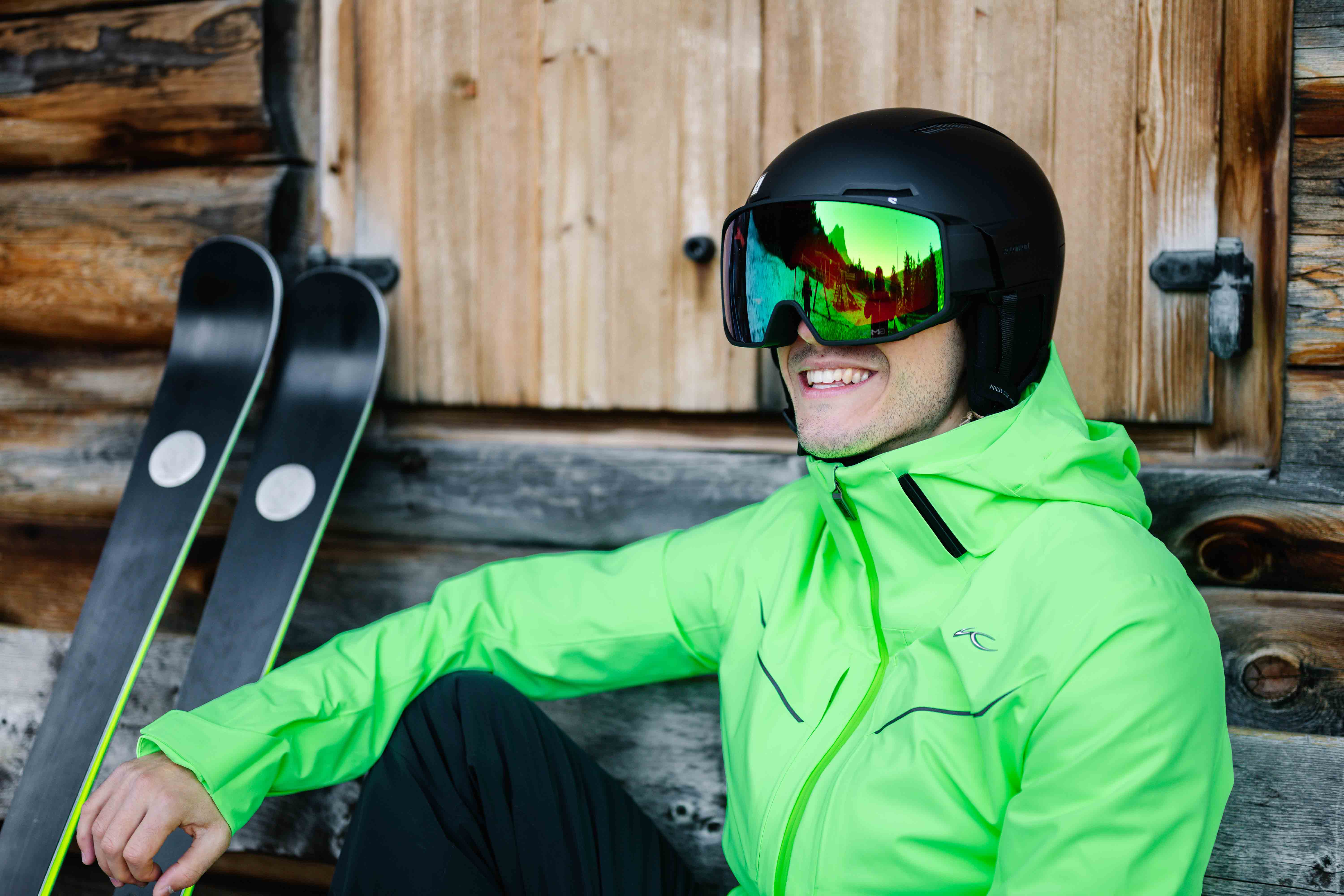 Skifahrer mit leuchtend grüner Jacke, Helm und Skibrille