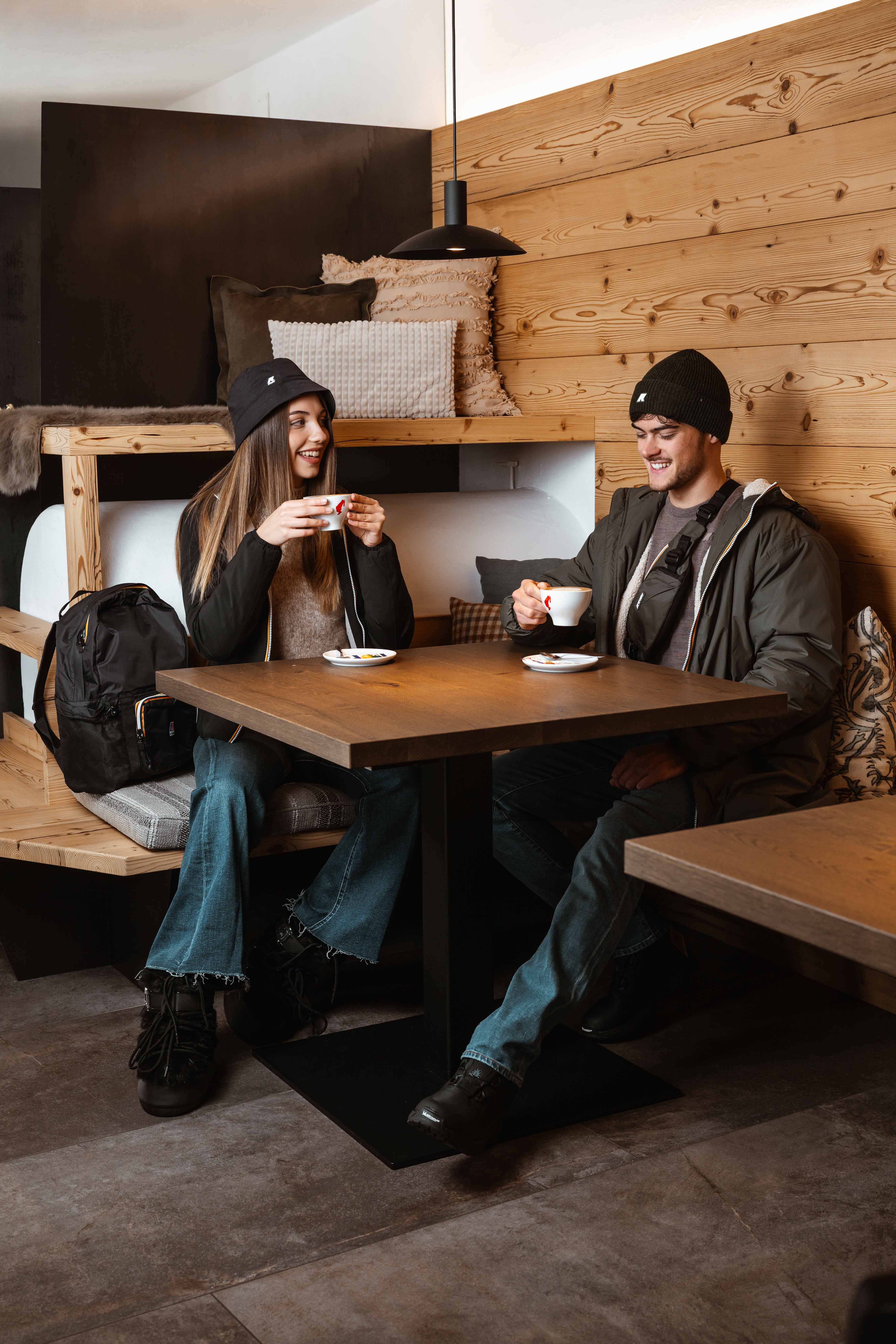 Zwei Personen in dunkler Winterkleidung an einem Holztisch