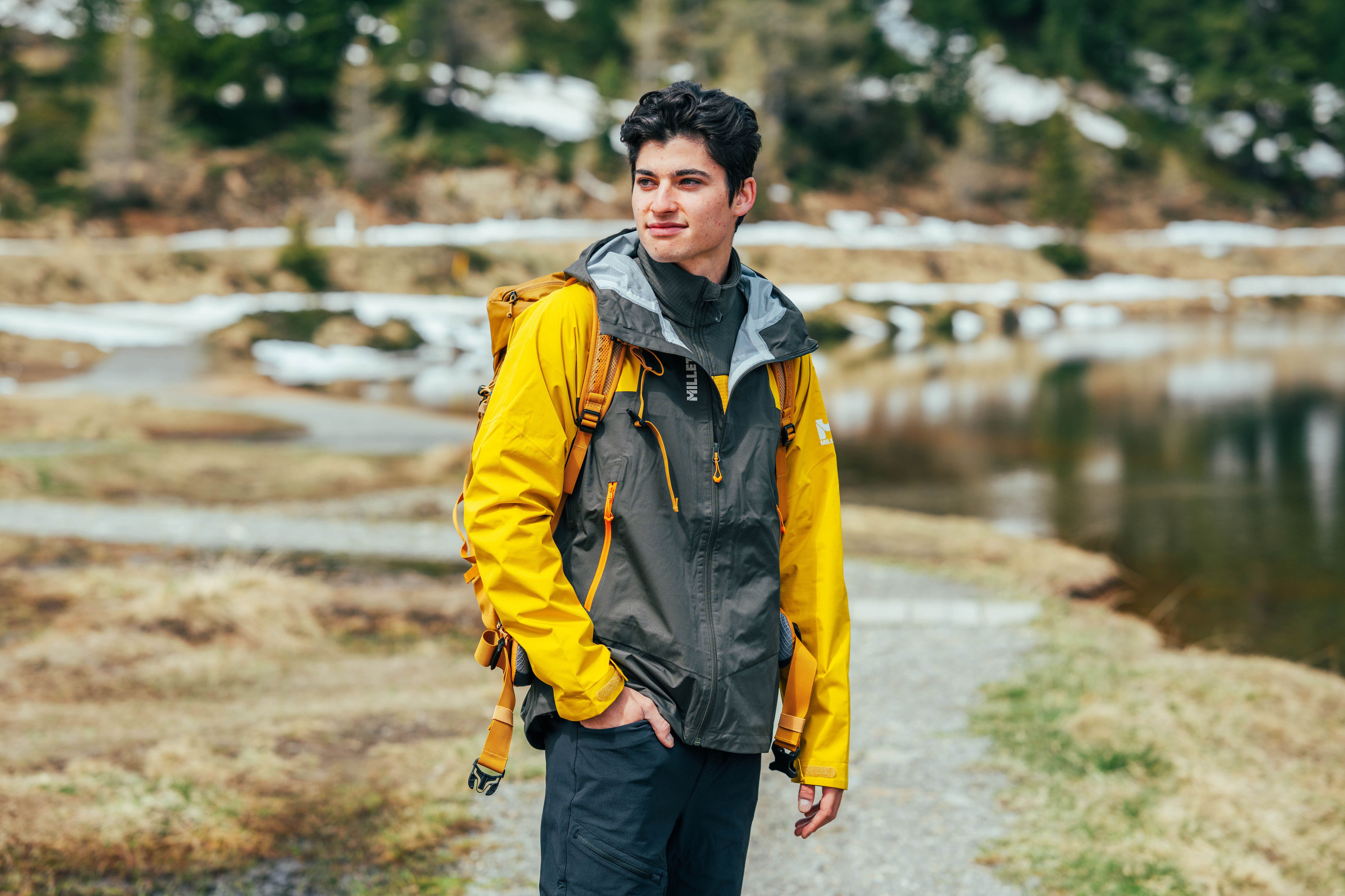 Mann mit gelber Outdoorjacke am Bergsee